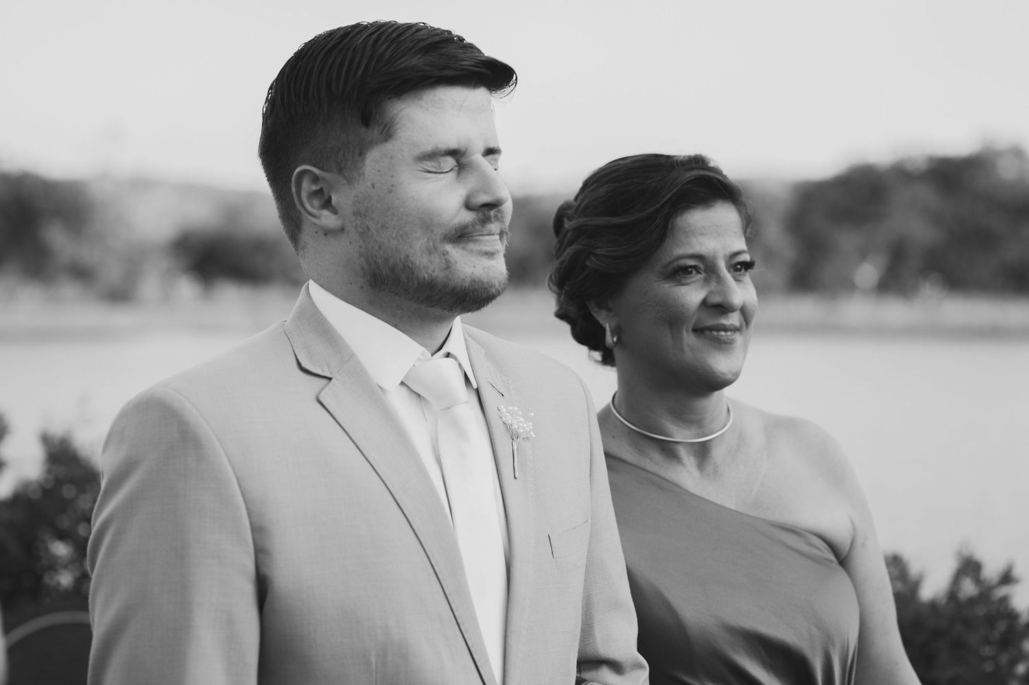 Black and white portrait of a stylish couple in formal attire standing outdoors.