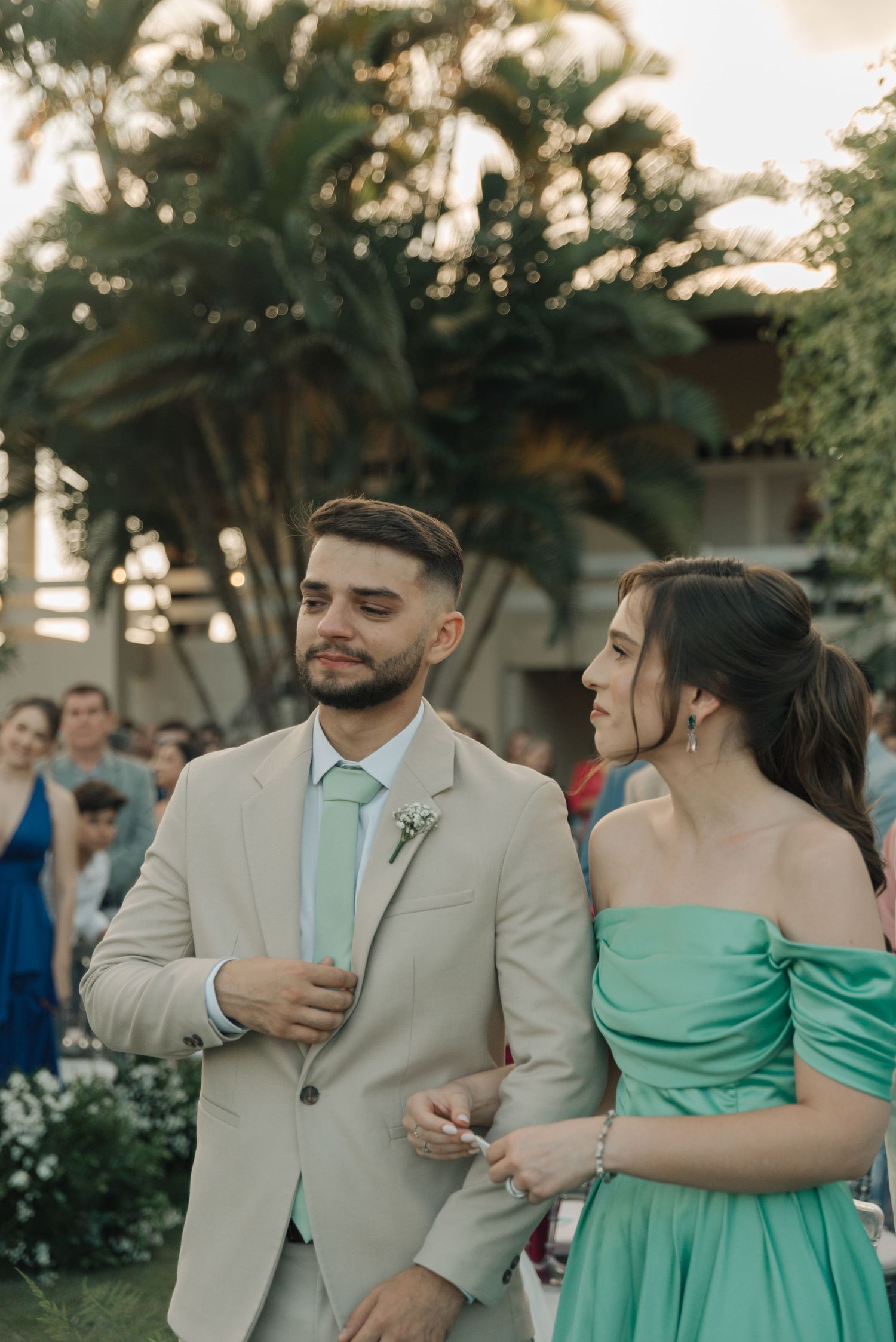 Wedding party members in coordinated mint and beige outfits at an outdoor garden venue.