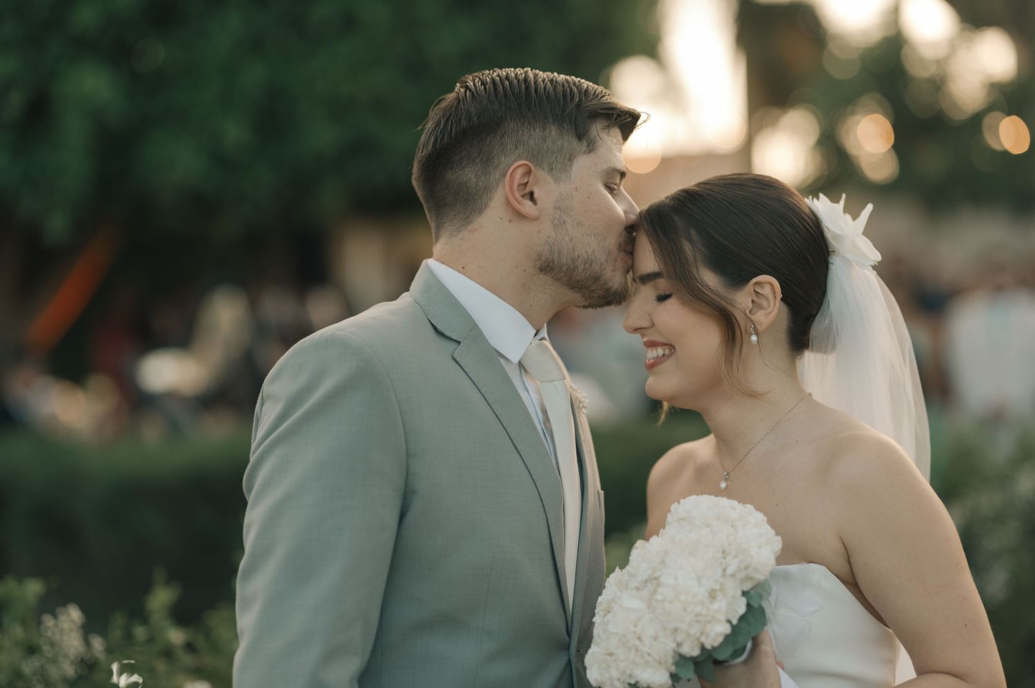 Tender moment shared between newlyweds in a garden setting at sunset.
