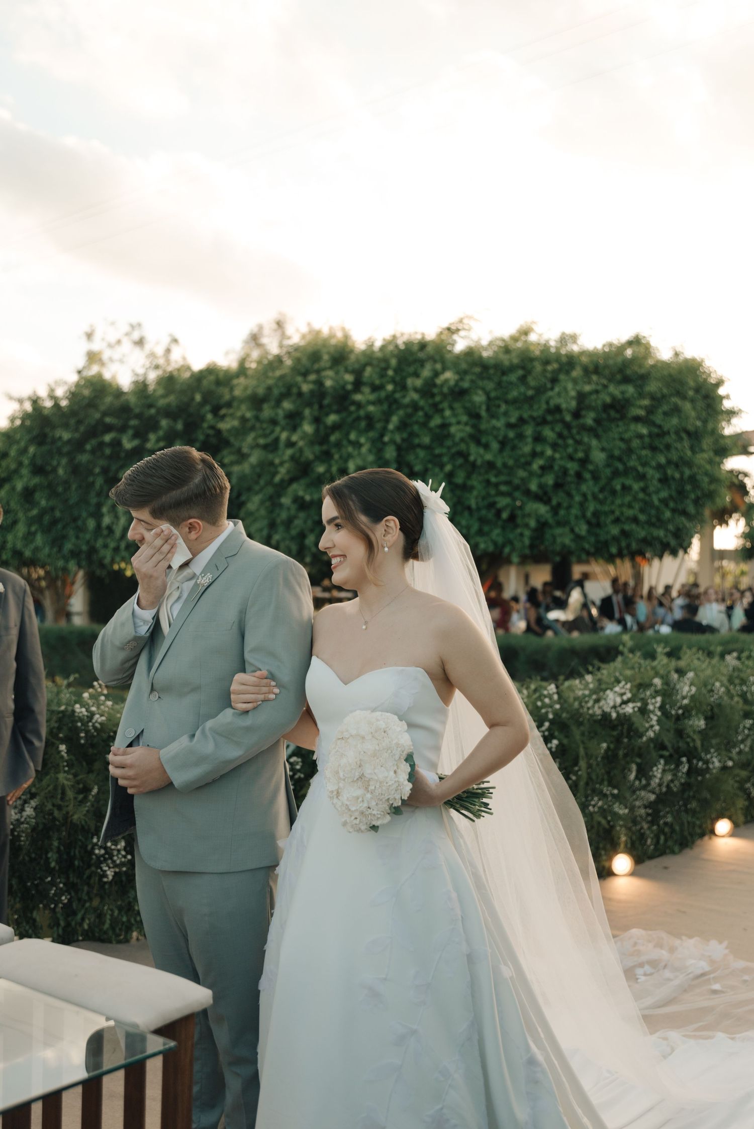 Emotional wedding moment captured in a garden setting with soft evening lighting.