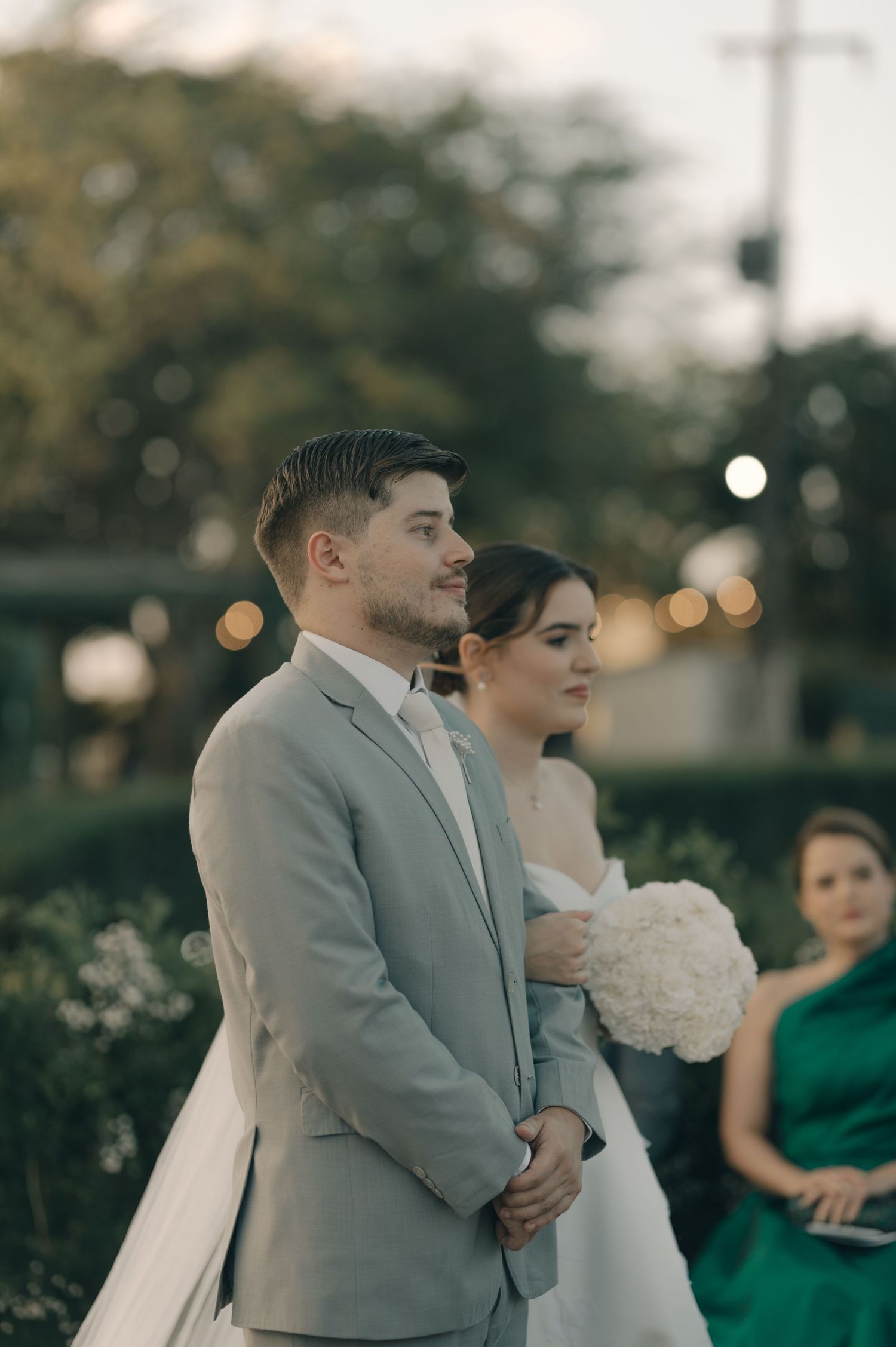 A couple stands together during their sunset wedding ceremony with guests in attendance.