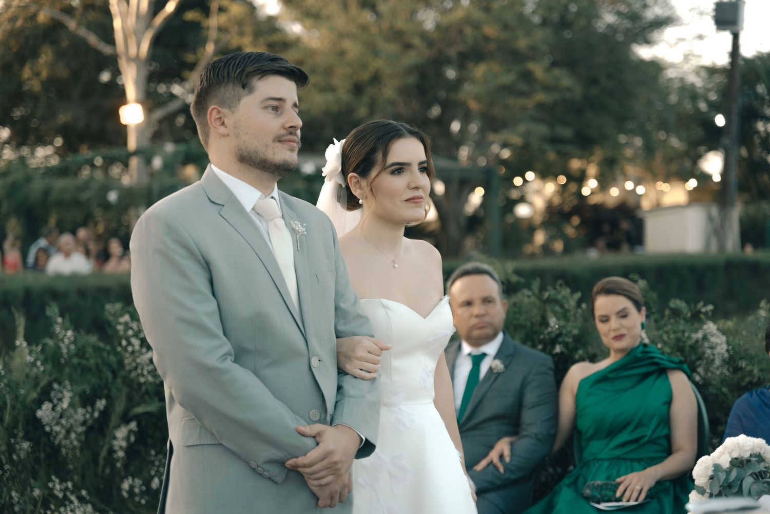 Outdoor wedding ceremony with couple standing together and wedding party in the background.