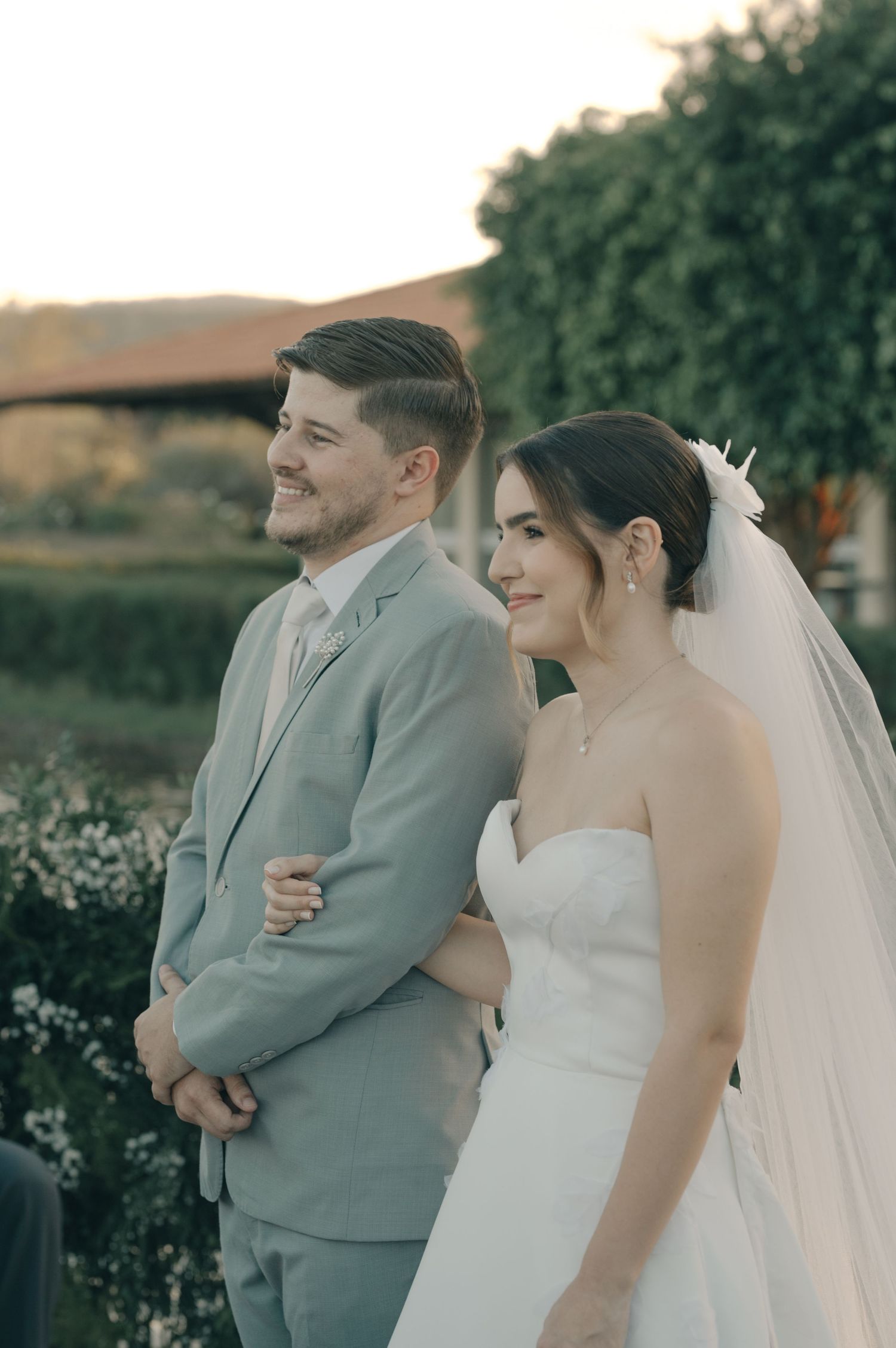 A bride and groom stand together during their sunset outdoor wedding ceremony.