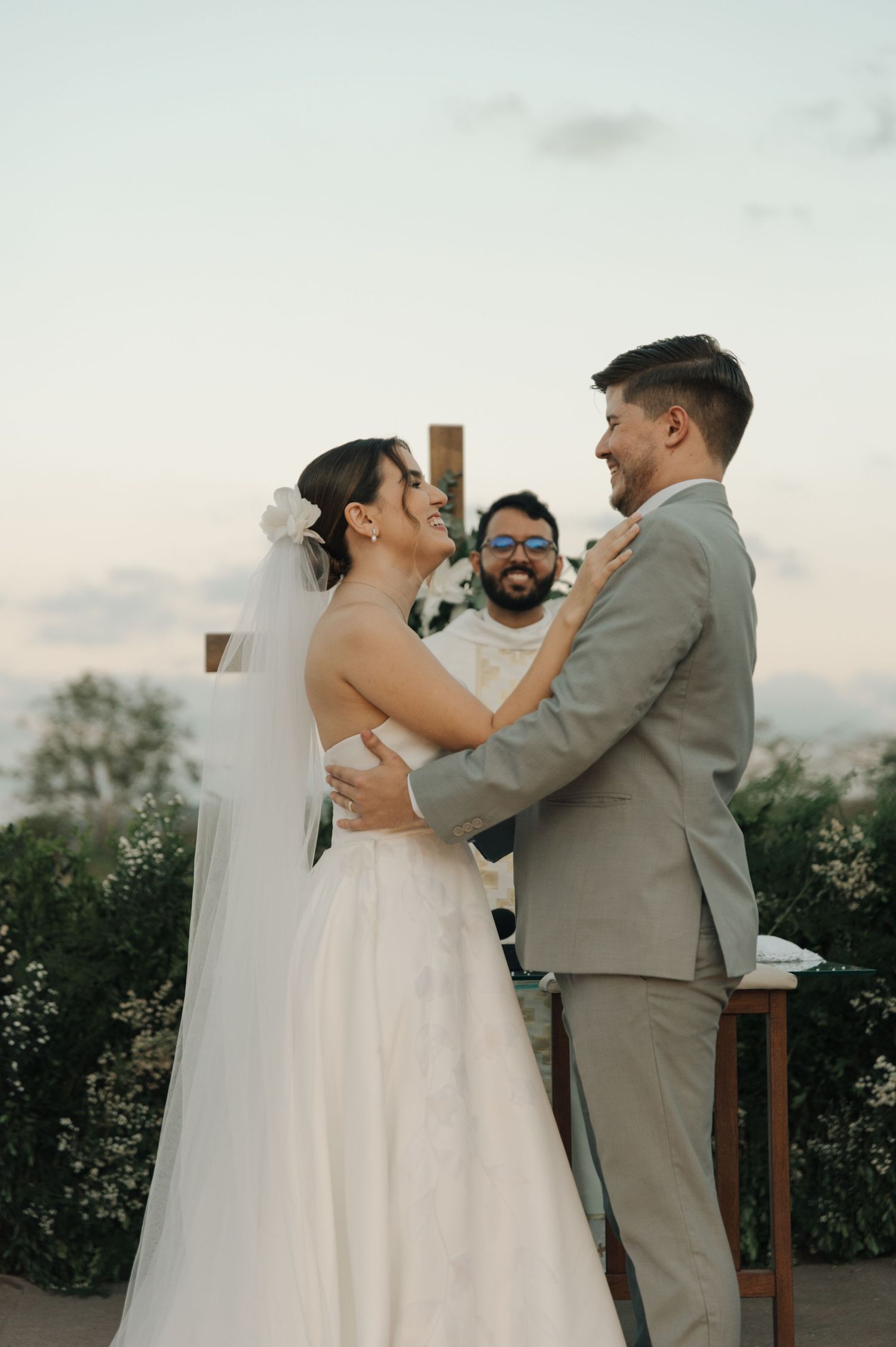 Couple exchanges vows during intimate outdoor ceremony with officiant in background.
