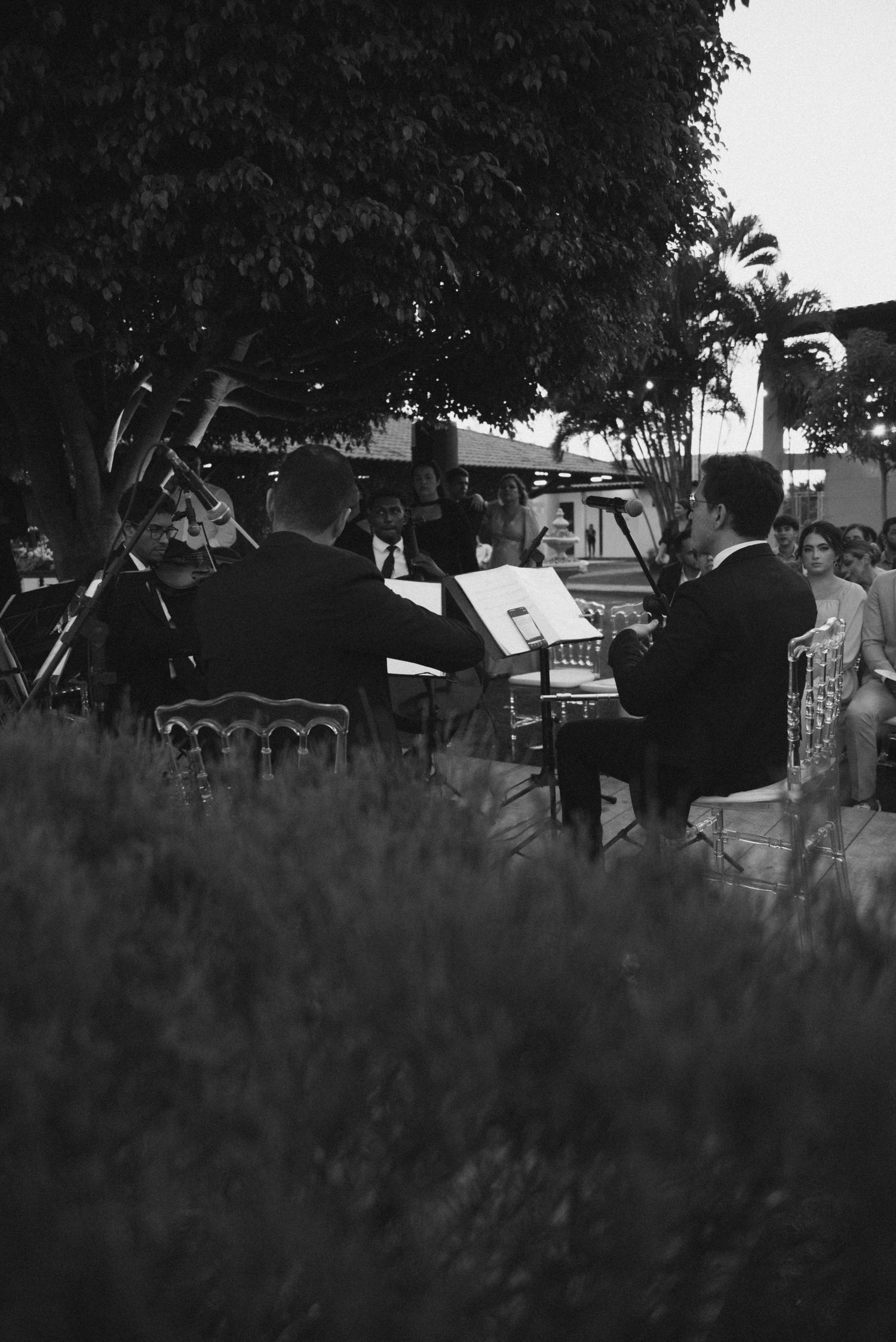 Black and white photo of musicians performing at an outdoor wedding reception.