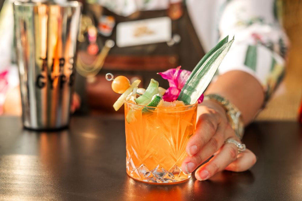 Tropical cocktail garnished with fresh flowers and fruit in an elegant crystal glass.