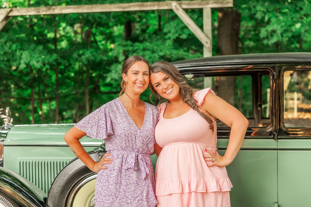 Two festive dresses styled against a mint green vintage automobile in a woodland setting.