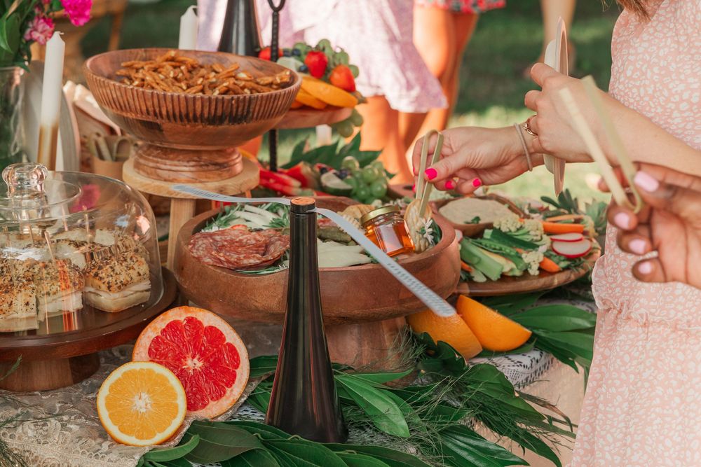 Food and drink spread with citrus fruits and appetizers on decorated outdoor table.