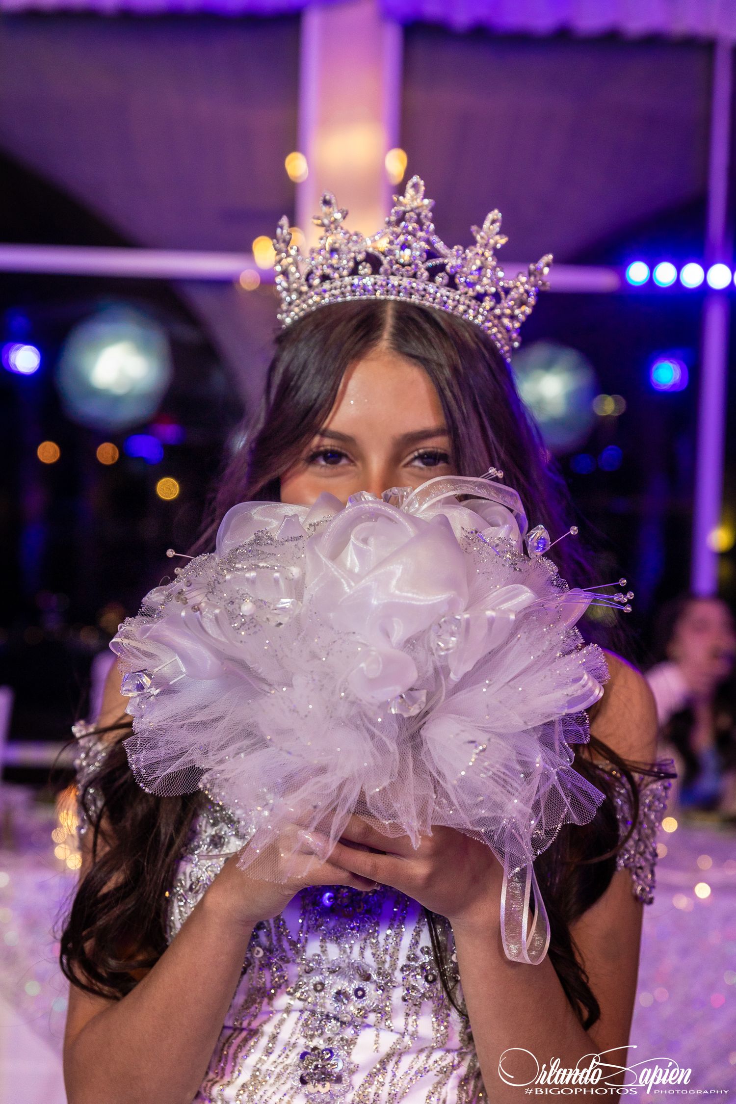 A quinceañera celebration with purple lighting and a sparkling tiara worn by someone in a white dress.