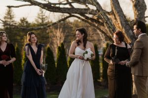 A wedding party poses during an outdoor ceremony with evergreen trees in the background.