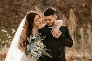 Romantic outdoor wedding portraits of couple embracing in autumn setting with natural lighting.