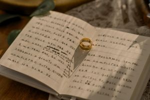Handwritten wedding vows on paper with wedding rings casting shadows in warm lighting.