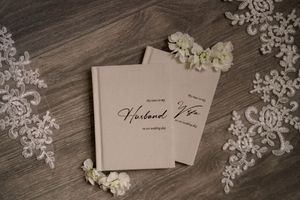 Elegant wedding place cards with calligraphy displayed on a rustic wooden surface with delicate white lace details.