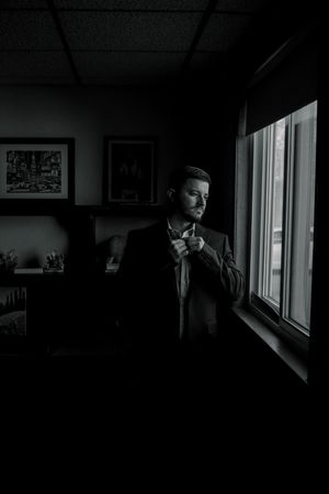 A dramatic black and white photograph showing a silhouette against a bright window in a dark room.