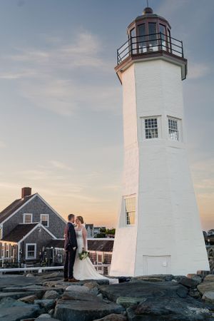 A coastal lighthouse provides a stunning backdrop for wedding photos at sunset.