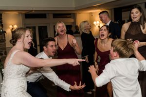 Wedding reception guests dancing and celebrating energetically on the dance floor.