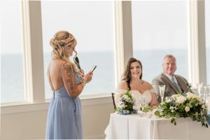 Wedding toast being given during the reception with ocean views through large windows.