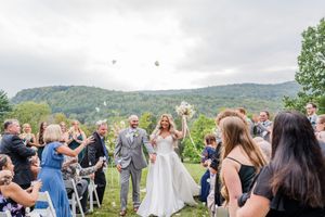 Wedding guests celebrating and cheering during an outdoor ceremony with mountain views.