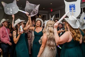 Wedding guests dance and celebrate together on a dimly lit dance floor at a reception party.