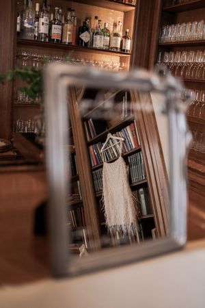 Wedding rings displayed in elegant frames at a rustic wooden bar with glassware and bottles in the background.