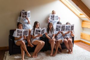 Group wearing matching robes reads newspapers while relaxing on a couch.