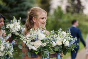 Elegant bridesmaid holding a lush white and green floral bouquet outdoors.