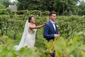 Playful first look scene between newlyweds among vineyard rows.