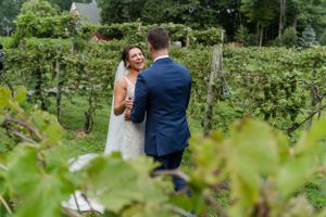 A romantic moment between newlyweds surrounded by lush green vineyard vines.