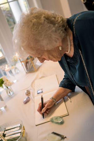 Someone writes in a guest book at an elegant event with crystals and decorative elements on the table.
