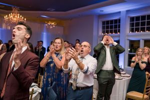 Wedding guests dancing and celebrating at a reception with blue ambient lighting.