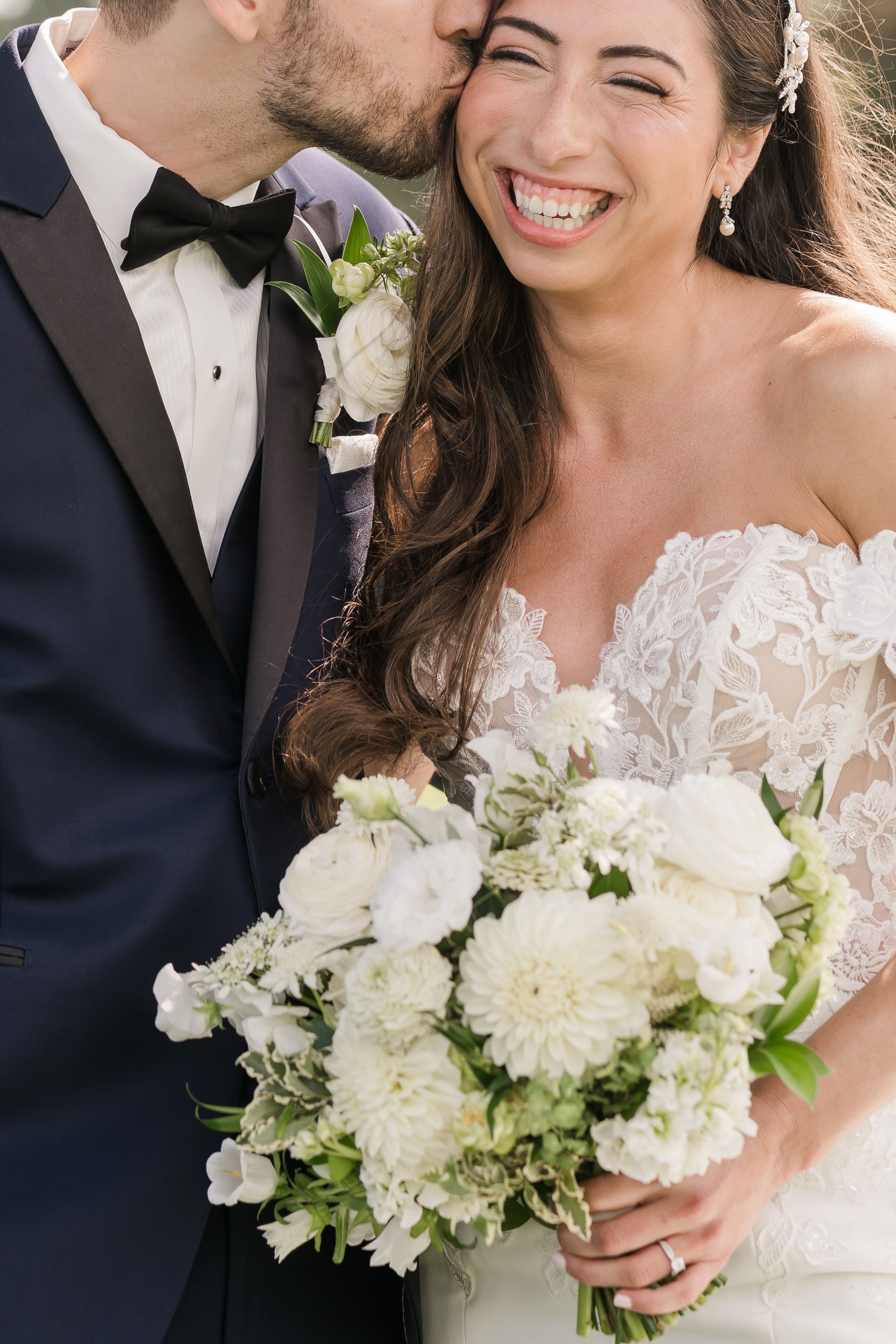 Newlyweds share a joyful moment with white floral bouquet during their wedding celebration.