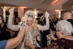Wedding party dancing and celebrating with raised arms on a lively dance floor.