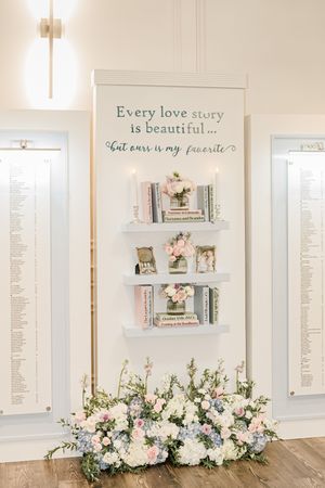 A romantic wall display with floating shelves, books, and floral arrangements beneath a love story quote.