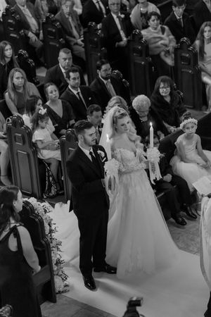 A wedding ceremony taking place in a church with guests seated in pews and a couple standing at the altar.
