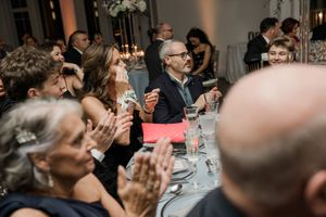 Wedding guests raise their glasses in a celebratory toast during an elegant indoor reception.