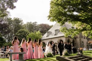 Wedding party celebrating on a manicured lawn in front of an elegant white house.