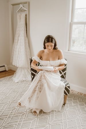 A white wedding dress being held up in a bright room with geometric patterned carpet.