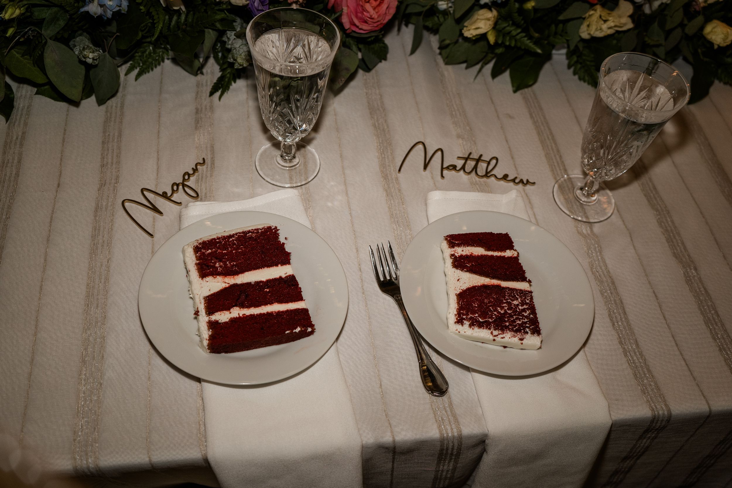 Slices of red velvet cake plated on white dishes with decorative place settings.