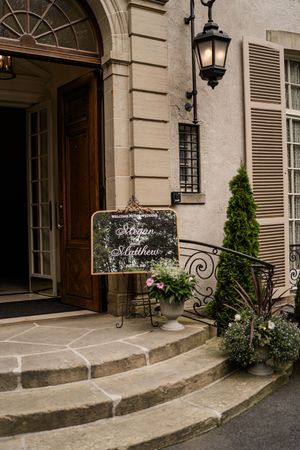 Elegant stone entrance steps with decorative signage and lanterns at a classic building facade.