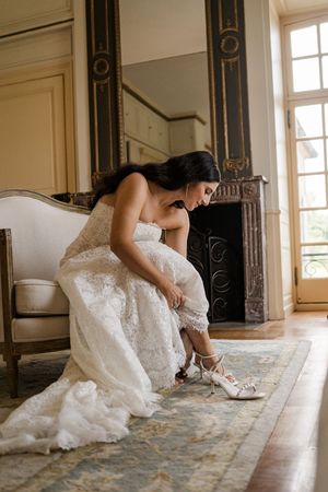 A sequence showing someone in a white lace wedding dress sitting and writing on a wooden floor in an elegant room.
