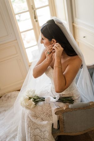 A flowing white wedding gown with delicate lace details is captured in soft natural light.