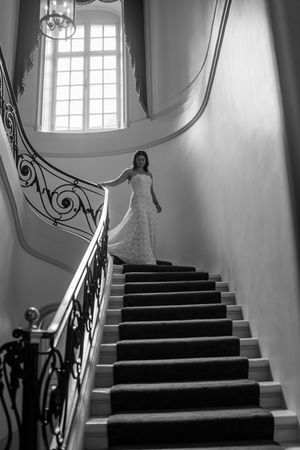 Elegant black and white staircase with ornate railing and natural light streaming through windows in a historic building.