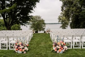 White wedding ceremony chairs set up on a lawn overlooking a scenic waterfront view.