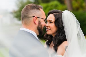 Intimate wedding portrait of couple sharing a close moment outdoors with natural greenery background.