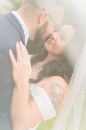 Soft, dreamy portrait of couple sharing an intimate moment through wedding veil.