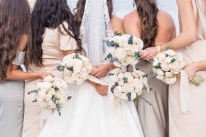 Bridesmaids holding matching white and cream floral bouquets.