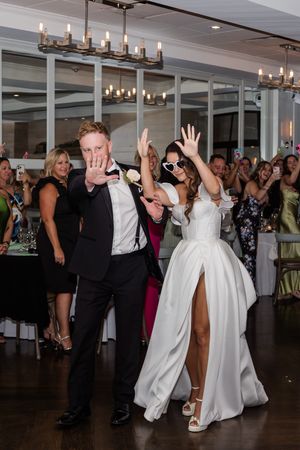 Festive reception scene with dancing and celebration in an indoor venue with chandelier lighting.