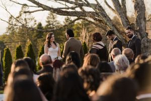 An intimate outdoor wedding ceremony surrounded by trees and natural scenery.