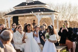 Wedding guests gathered around a white gazebo during an outdoor ceremony.