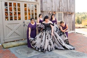 Wedding party in purple dresses poses in front of a rustic barn door.